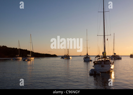 Sailboats moored on calm water with glow of rising sun at dawn at Saba Rock in the Caribbean British Virgin Islands Stock Photo