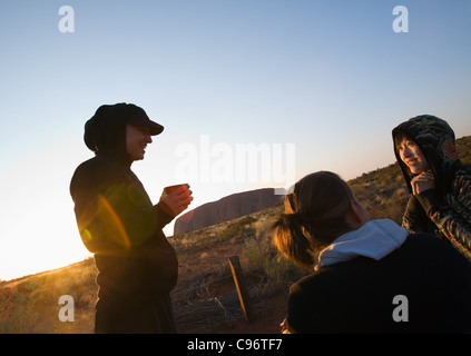 Group of young tourists enjoying the sunrise at Uluru (Ayers Rocks).  Uluru-Kata Tjuta National Park, Northern Territory, Austra Stock Photo