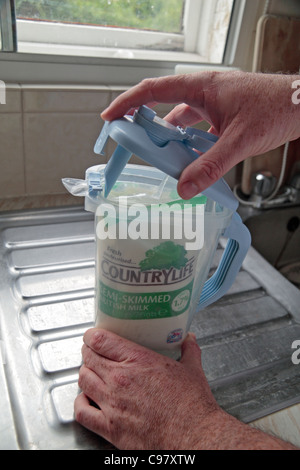 A man about to push the spout into a Jugit and milk bag sitting on a kitchen sink unit. Stock Photo