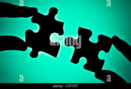 two hands connecting two pieces of puzzle Stock Photo