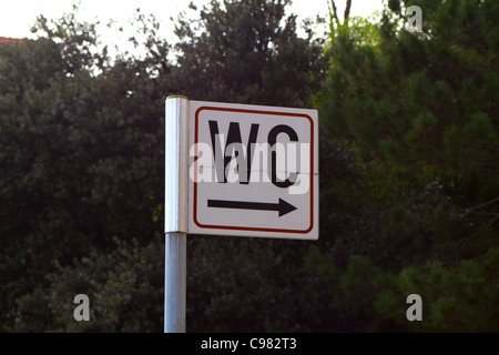 Sign for toilet - WC with arrow pointing to bushes Stock Photo