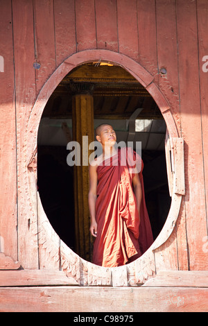 Young monks are watching from monastery oval window  in Shwe Yaunghwe monastery in Nyaungshwe, Shan state of Myanmar Stock Photo