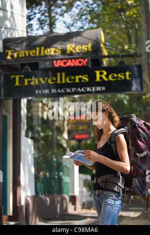 A backpacker reads her guidebook outside a hostel. Kings Cross, Sydney, New South Wales, Australia Stock Photo