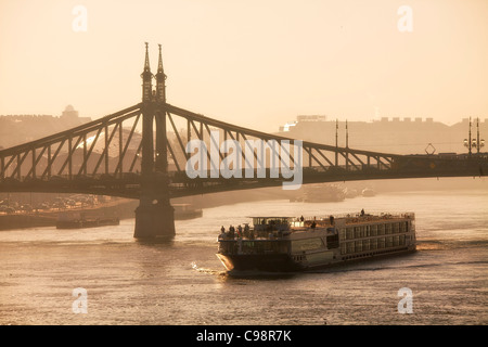 Budapest, Tour Boat on Danube River and Freedom Bridge at Sunrise Stock Photo
