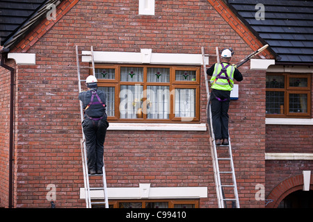 Men on climbing Ladders  Polystyrene Bead house cavity wall insulation, Workers in safety harness, installing Foam Insulation in Southport, UK Stock Photo