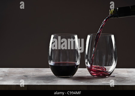 Pouring Red Wine into Glass against Brown Background Stock Photo