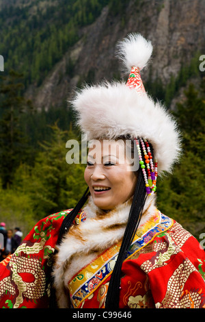 Chinese women tourist in traditional Tibetan national costume / dress, with fur hat & long sleeves. Jiuzhaigou Valley, China. Stock Photo