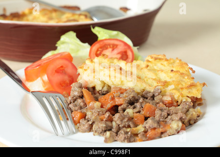 A dinner of shepherds pie or cottage pie and a salad with the serving dish in the background Stock Photo