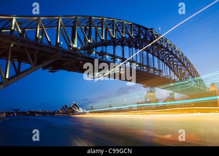 Light trails a passing ferry with the Harbour Bridge and Sydney Opera House in background. Sydney, New South Wales, Australia Stock Photo
