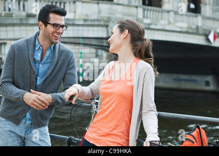 Germany, Berlin, Couple leaning on fence near river and talking Stock Photo