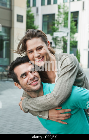 Germany, Berlin, Man carrying woman on back in city Stock Photo