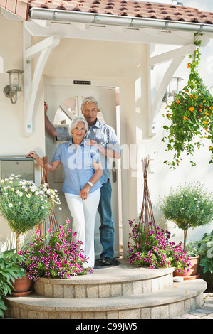 Germany, Bavaria, Mature man and senior woman in front of door, smiling Stock Photo