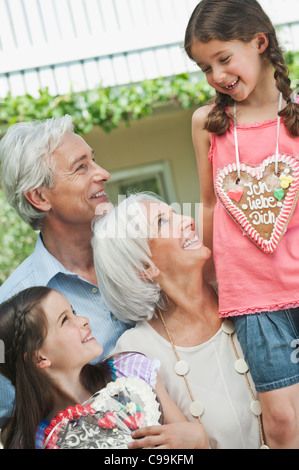 Germany, Bavaria, Grandparents with granddaughter holding gingerbread, smiling Stock Photo