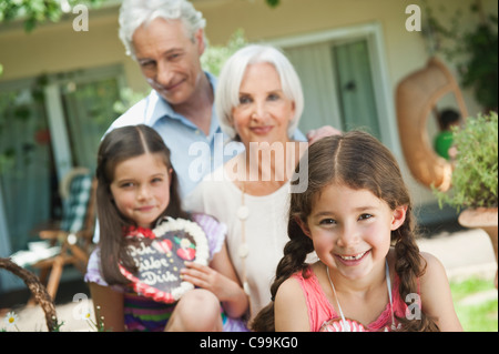 Germany, Bavaria, Grandparents with granddaughter holding gingerbread, smiling Stock Photo