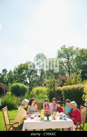 Germany, Bavaria, Family having coffee and cake in garden, smiling Stock Photo