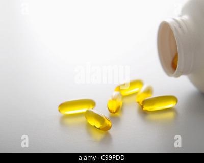 Pills spilling out of bottle on white background, close-up Stock Photo