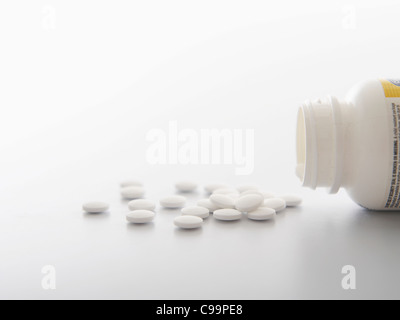 White pills spilling out of bottle, close-up Stock Photo