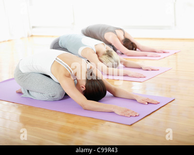 Germany, Hamburg, Yoga instructor and female trainee doing child's pose in gym room Stock Photo