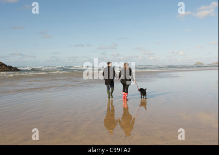 Young couple walking dog on a beach in winter. Stock Photo