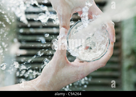 Italy, Tuscany, Magliano, Close up of woman's hand filling water glass Stock Photo