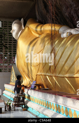 Woman worshipping in front of reclining golden Buddha statue at Wat Sai Thai temple. Krabi, Thailand, Southeast Asia, Asia Stock Photo