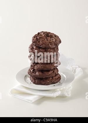 A tall stack of gourmet triple chocolate chip cookies on a white plate Stock Photo