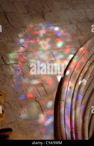 Scattered coloured light from a stained glass window on a cathedral wall Stock Photo