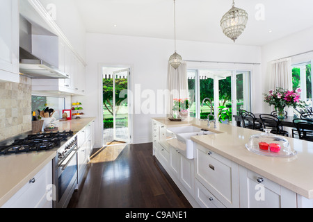 Stylish open plan kitchen with stainless steel appliances and dining area overlooking a pool and golf course Stock Photo