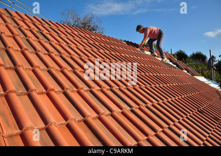 Lady fixing double roman tiles on roof UK Stock Photo