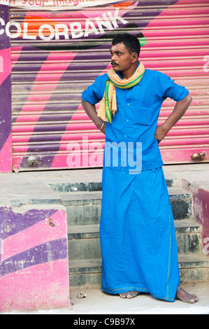 India man, hindu religious pilgrim dressed in blue standing next to colorbank sign. Puttaparthi, Andhra Pradesh, India Stock Photo