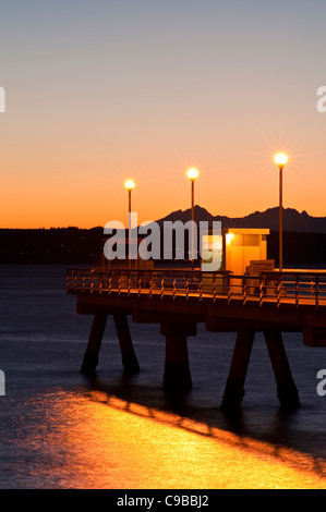 Silhouetted pier with people fishing off dock at sunset on Puget Sound with Olympic mountains Edmonds Washington State USA Stock Photo