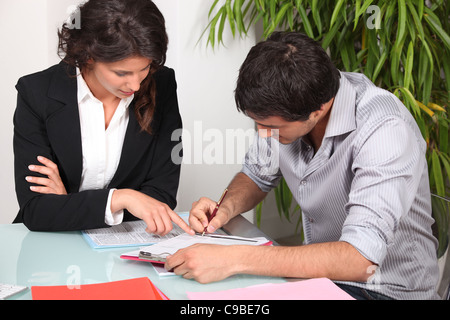 Businesswoman helping her client fill in paperwork Stock Photo