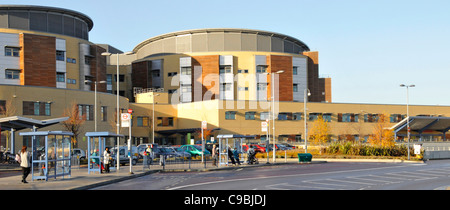 Bus stop & exterior of NHS Queens Hospital building & Maternity healthcare medical centre Romford London Borough of Havering East London England UK Stock Photo