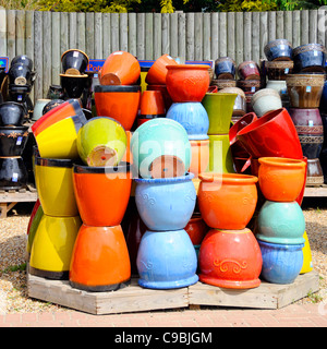 Stacks of colourful ceramic glazed ornamental plant pots on display for sale in retail garden centre business in Essex England UK Stock Photo