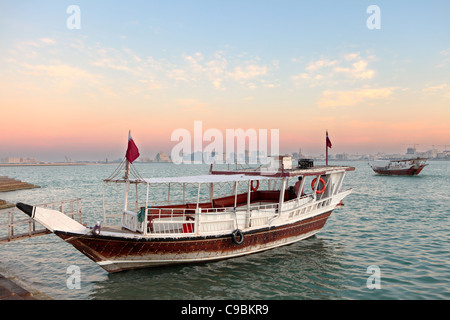 Sunset over Doha Bay, Qatar, Nov 20, 2011, with two of the excursion dhows that take visitors on short sightseeing trips along t Stock Photo