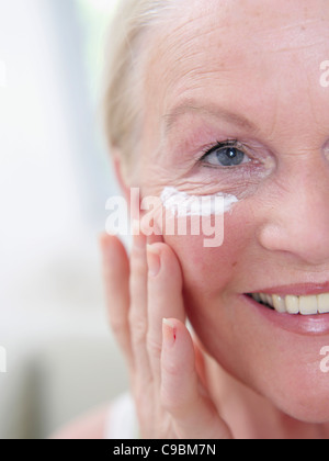 Senior woman applying face cream on face, close up Stock Photo