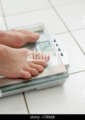 Mature woman standing on weight machine, close up Stock Photo