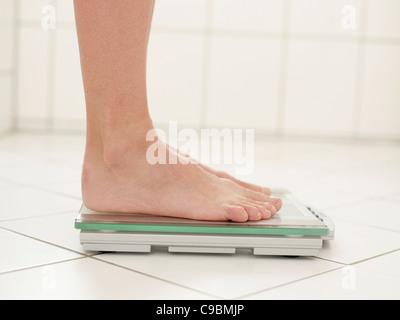 Mature woman standing on weight machine, close up Stock Photo