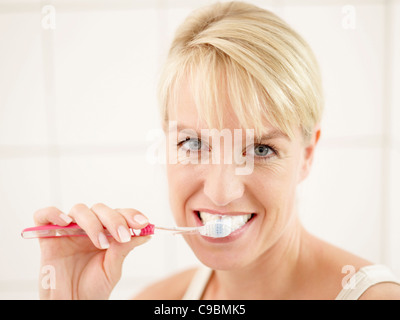 Close up of mature woman doing brushing her teeth, smiling, portrait Stock Photo