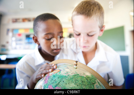 Two boys looking at globe in classroom, Johannesburg, Gauteng Province, South Africa Stock Photo