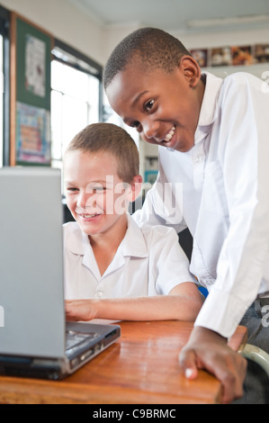 Two boys using laptop in classroom, Johannesburg, Gauteng Province, South Africa Stock Photo