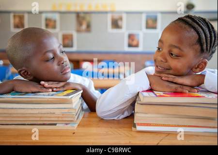 Boy and girl leaning on books at desk in classroom, Johannesburg, Gauteng Province, South Africa Stock Photo