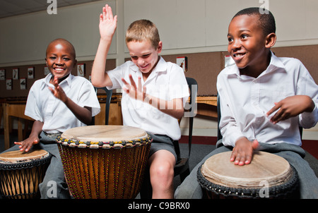 Three boys playing wooden hand drums in classroom, Johannesburg, Gauteng Province, South Africa Stock Photo