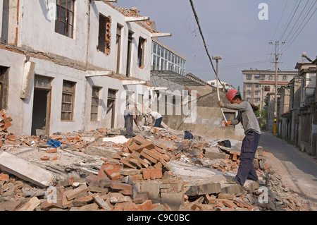 China, Jiangsu, Qidong, Demolition workers using hammers with flexible handles to demolish old residential buildings. Stock Photo