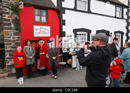 Tourists pose for a photographs outside the 'Smallest House in Great Britain', Conwy, Wales Stock Photo