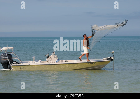 Man throwing a fishing net from a small boat on the Gulf Coast