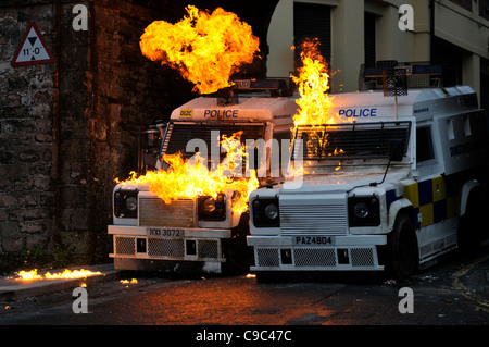 PSNI officers (left) shelter behind armoured Landrovers during a sustained petrol bomb attack by nationalist youths in the Bogsi Stock Photo