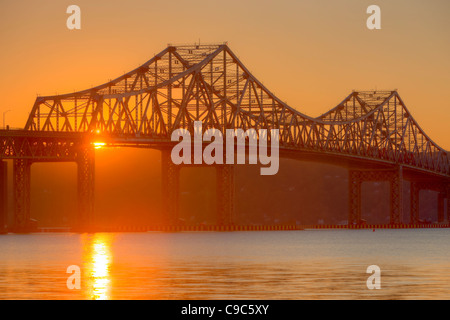 The sun sets behind the Tappan Zee Bridge and reflects off the surface of the Hudson River. Stock Photo