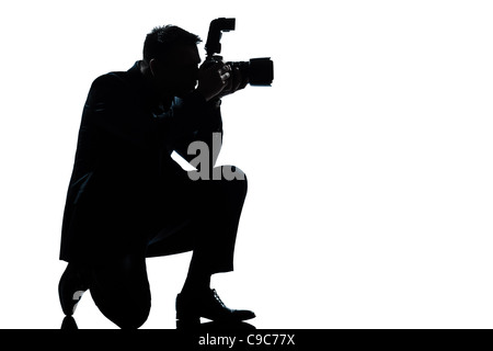 one  man kneeling photographer full length silhouette in studio isolated on white background Stock Photo