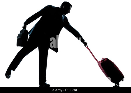 one  man with his suitcase pulling him full length silhouette in studio isolated white background Stock Photo